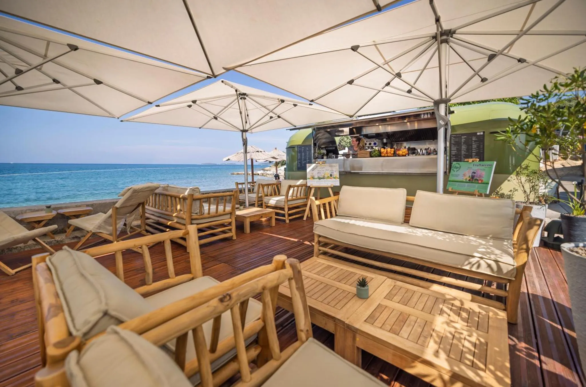 Terrasse aménagée avec des salons et des transats en bord de mer.