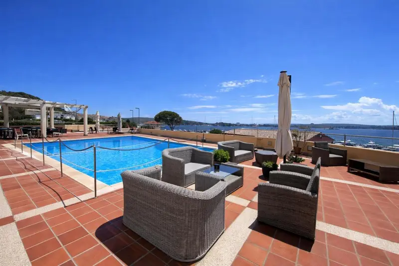 Terrasse avec piscine et mobilier de jardin face à la mer.