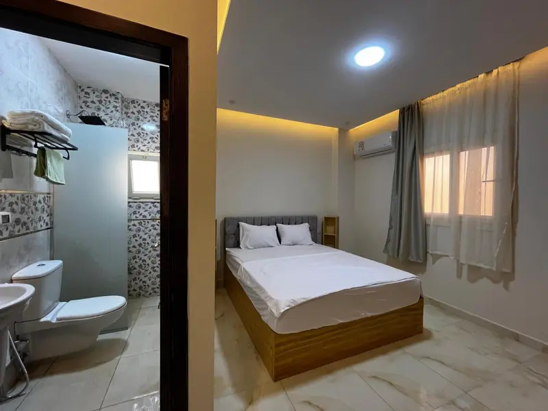 Une chambre lumineuse avec un lit double et une salle de bain attenante.