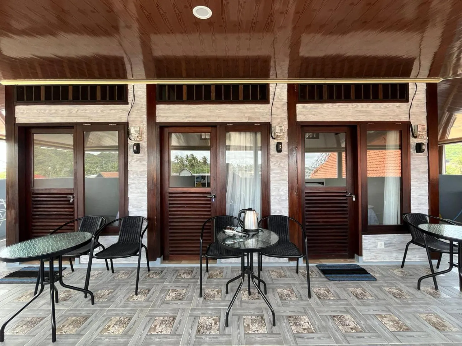 Terrasse avec tables et chaises devant des portes vitrées.