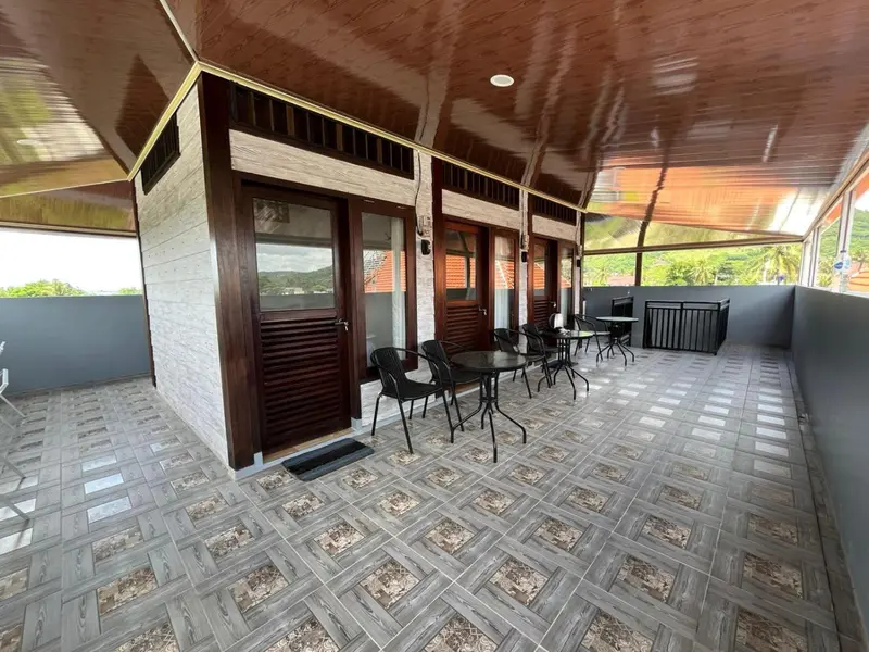 Terrasse carrelée avec mobilier de jardin et accès à des pièces.