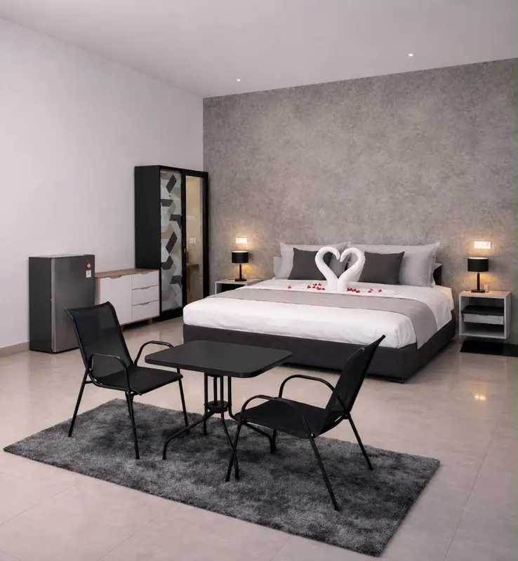 Une chambre avec un lit décoré de pétales de roses et une petite table avec des chaises.