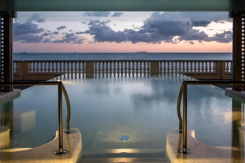Une piscine à débordement offre une vue sur la mer au coucher du soleil.