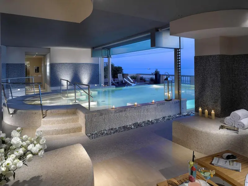 Espace de relaxation avec piscine intérieure et vue sur la mer.