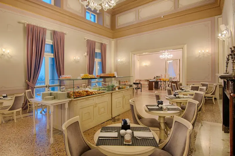 Une salle lumineuse avec des tables dressées et un buffet de pâtisseries.