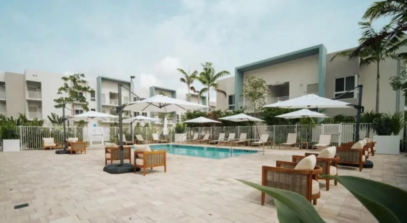 Terrasse avec transats et parasols autour d'une piscine ensoleillée.