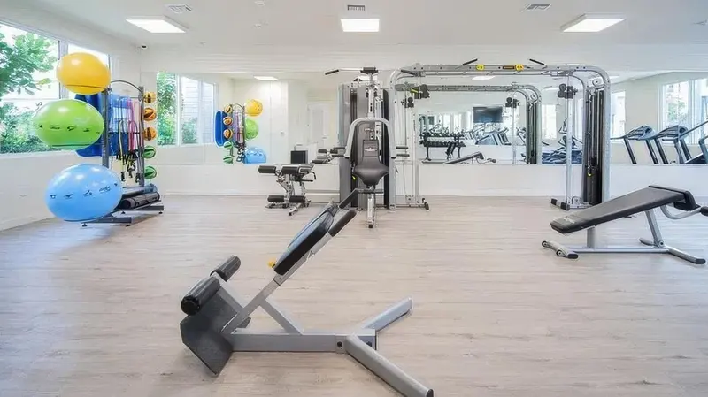 Une salle de sport lumineuse avec des équipements de musculation et des ballons.