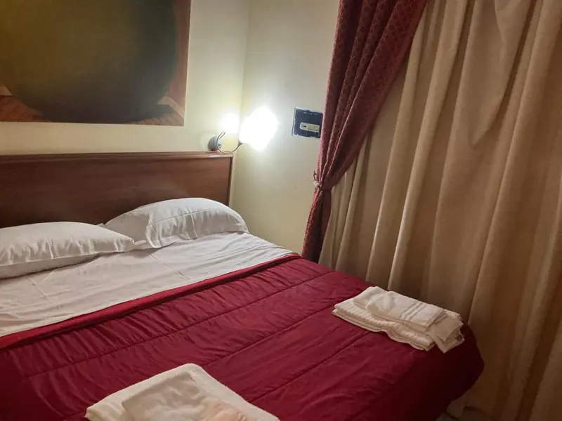 Une chambre avec un lit recouvert d'une courtepointe rouge et des oreillers blancs.