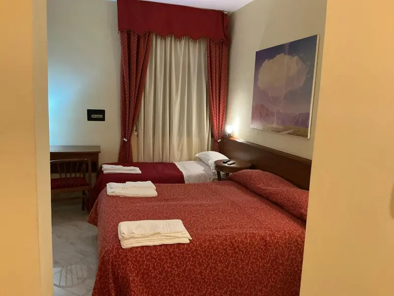 Une chambre avec deux lits simples décorés de textiles rouges.