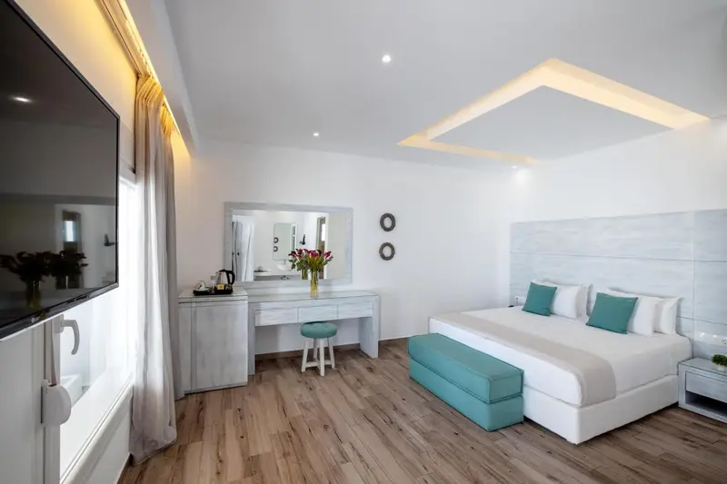 Une chambre lumineuse avec un grand lit et un coin coiffeuse.
