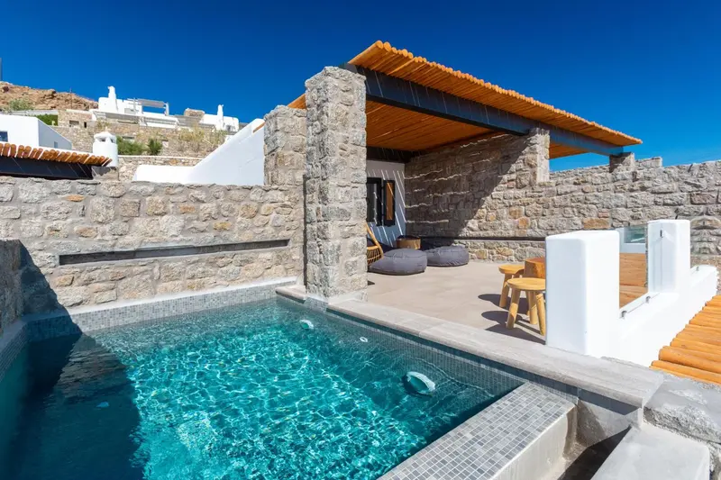 Petite piscine et terrasse aménagée avec des sièges et une table basse.