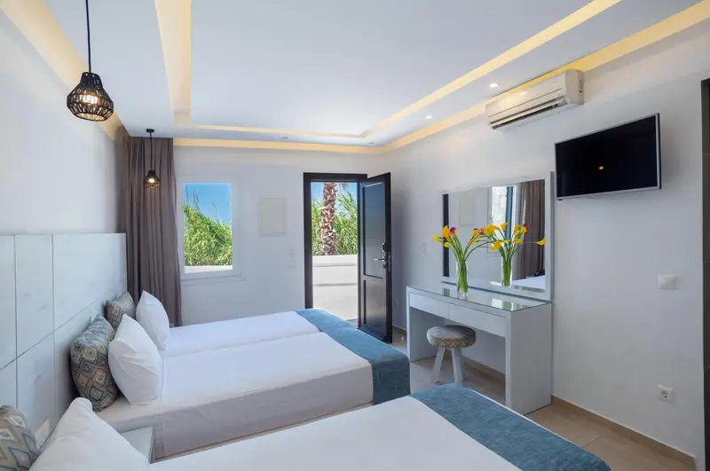 Une chambre lumineuse avec deux lits simples et un espace coiffeuse.