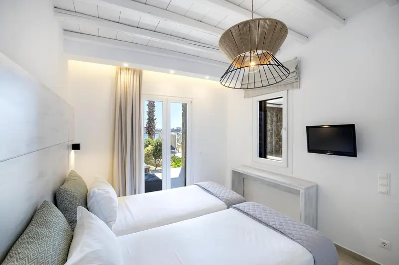 Une chambre lumineuse avec deux lits simples et une vue sur la mer.