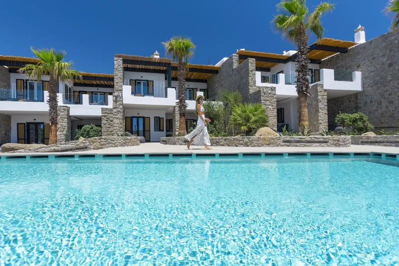 Vue d'un bâtiment blanc avec des palmiers et une piscine turquoise.