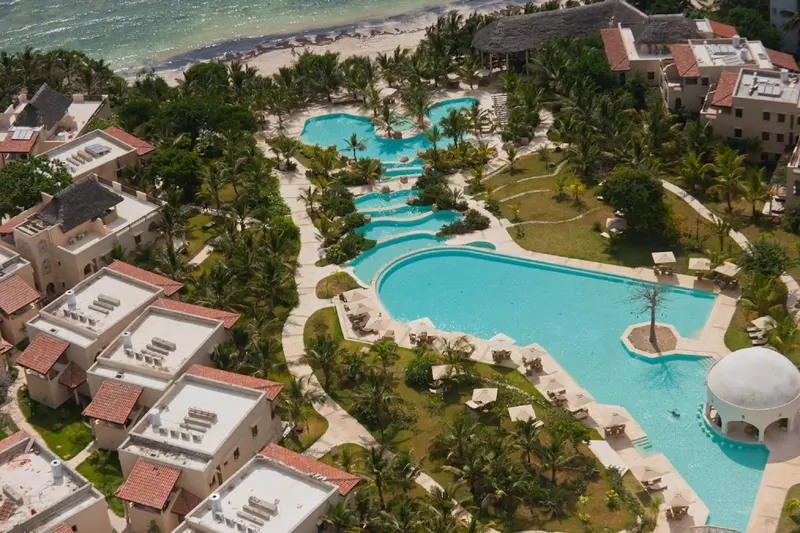 Vue aérienne d'un complexe hôtelier avec des piscines et une végétation luxuriante.