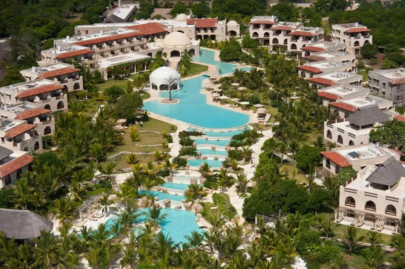 Vue aérienne d'un complexe hôtelier avec une grande piscine sinueuse et une végétation luxuriante.