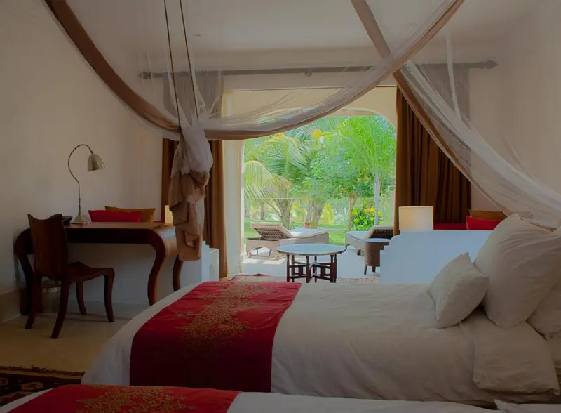 Une chambre lumineuse avec un lit recouvert d'une moustiquaire donnant sur une végétation luxuriante.