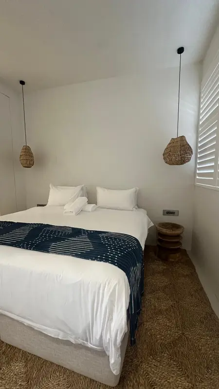Une chambre lumineuse avec un grand lit recouvert d'une courtepointe bleu marine.
