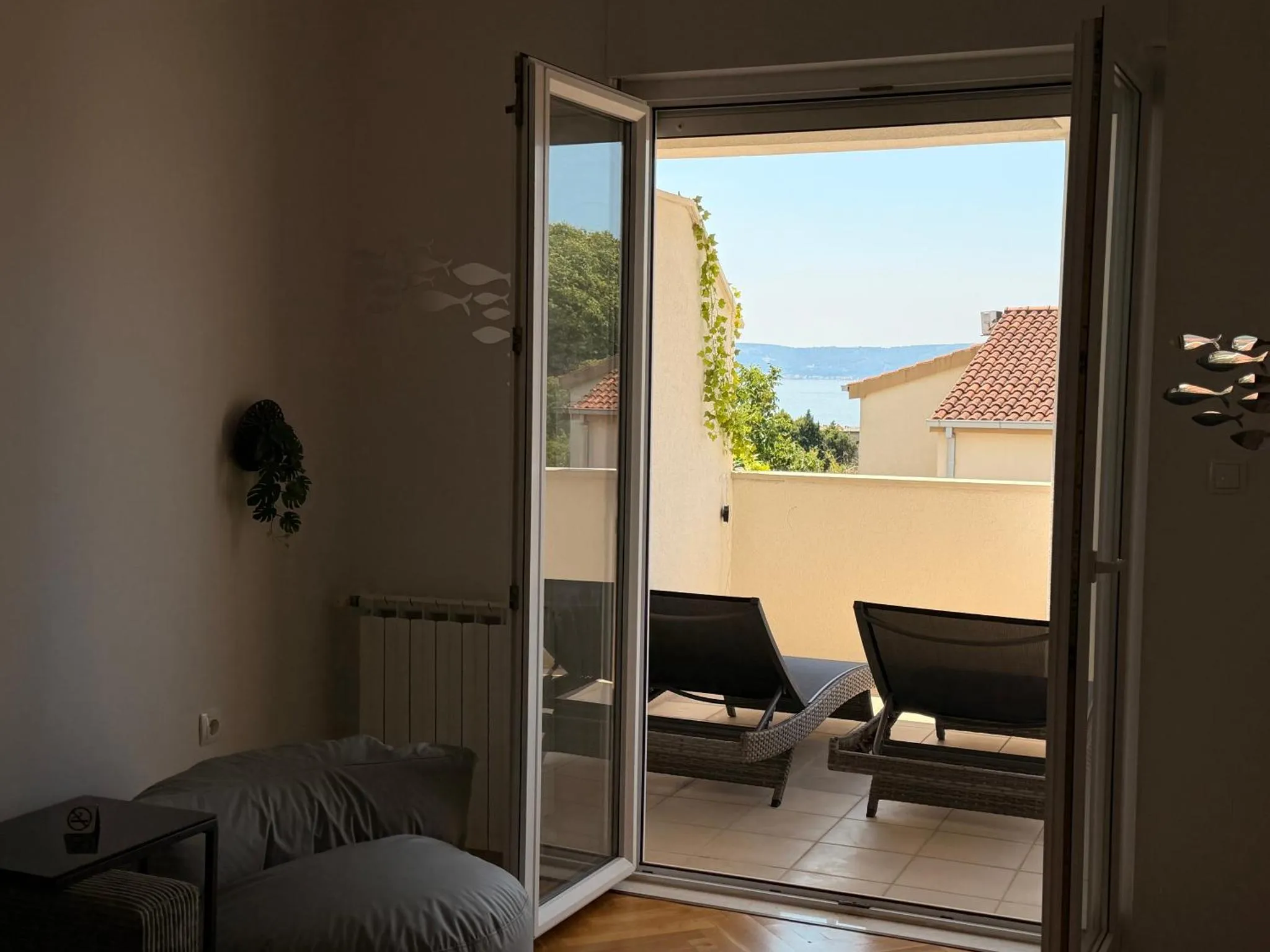 Une terrasse ensoleillée offre une vue sur la mer et les toits.