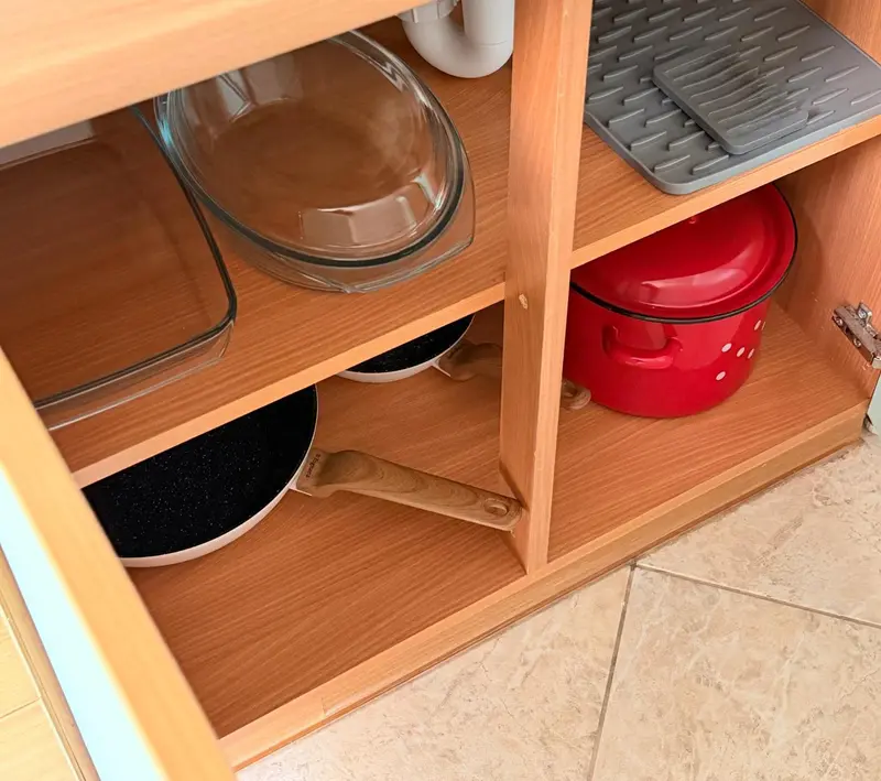 Vaisselle et ustensiles de cuisine rangés dans un meuble.