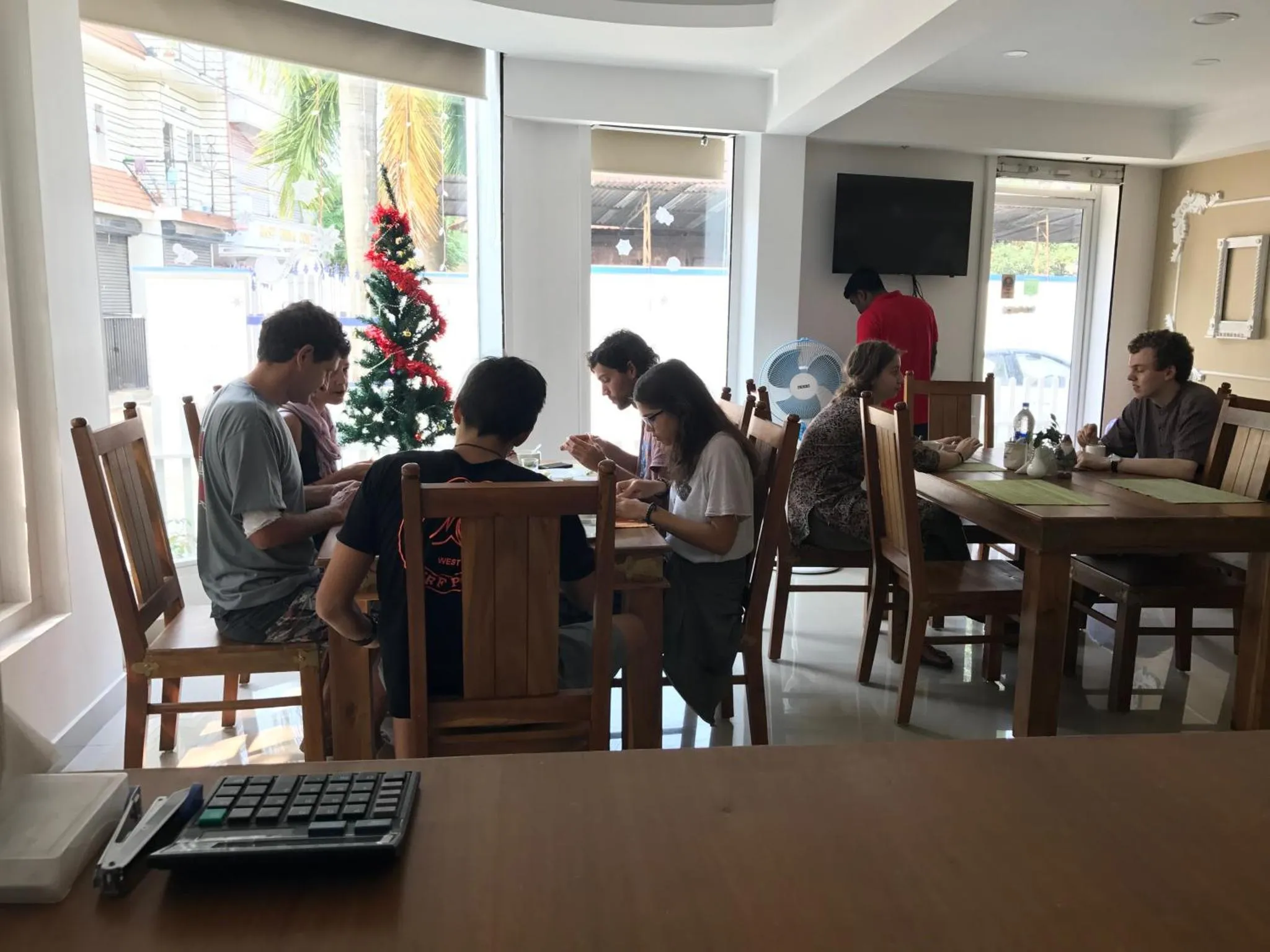 Des personnes sont assises autour d'une table en bois dans une salle lumineuse.