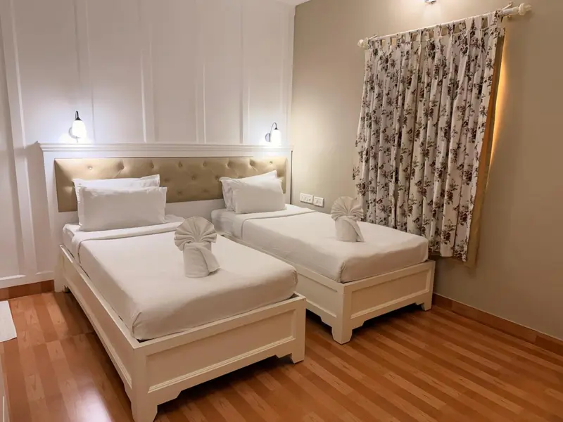 Une chambre lumineuse avec deux lits simples et des oreillers blancs.