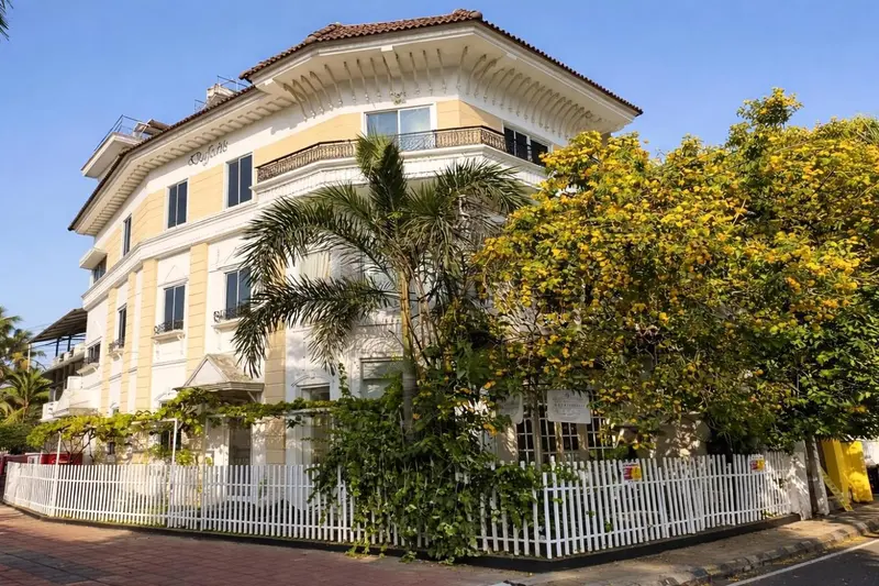 Bâtiment jaune à plusieurs étages avec des balcons et une végétation luxuriante.