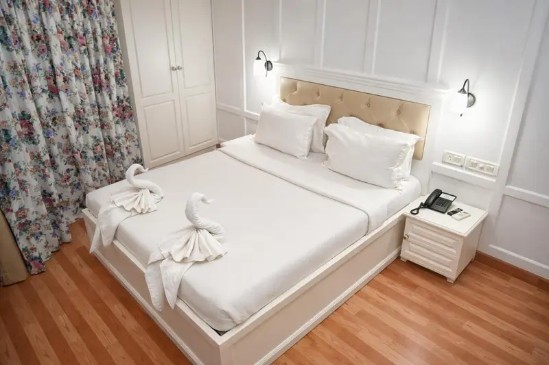 Une chambre lumineuse avec un grand lit recouvert de draps blancs et de serviettes en forme de cygnes.