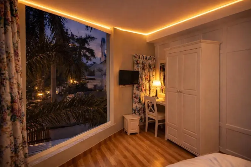 Une chambre lumineuse avec un bureau et une vue sur la végétation.