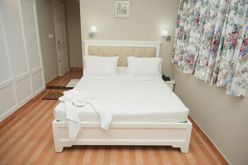 Une chambre lumineuse avec un grand lit blanc et des rideaux fleuris.