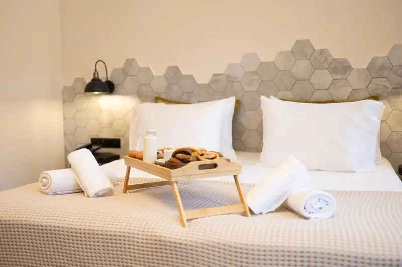 Un lit préparé avec un plateau de petit-déjeuner et des serviettes.