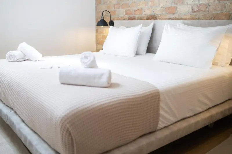 Un lit double est soigneusement fait avec des draps blancs et des oreillers moelleux.
