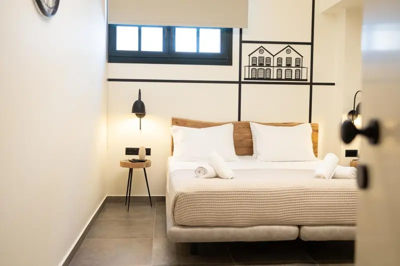 Une chambre lumineuse avec un grand lit et une décoration murale graphique.