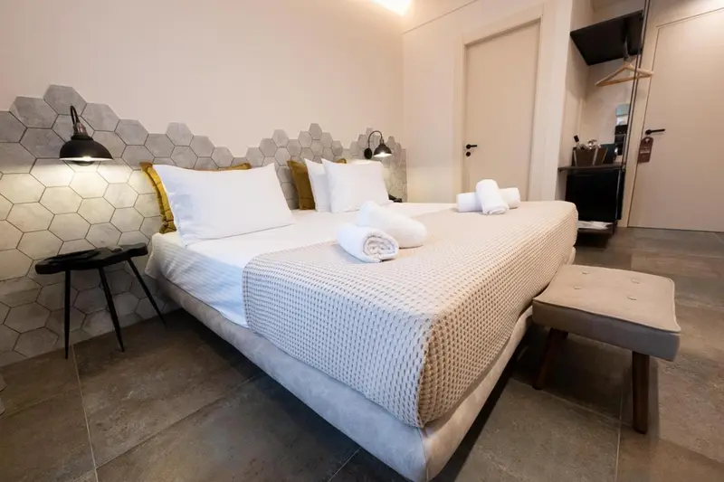 Une chambre lumineuse avec un grand lit recouvert d'une courtepointe blanche et de coussins.