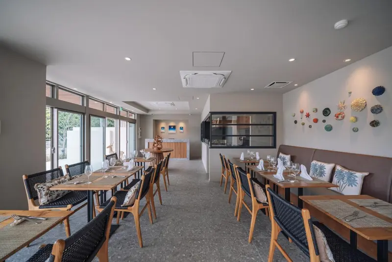 Une salle lumineuse avec des tables dressées pour un repas.