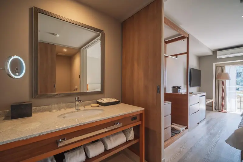 Une salle de bain lumineuse avec un grand miroir et des serviettes.