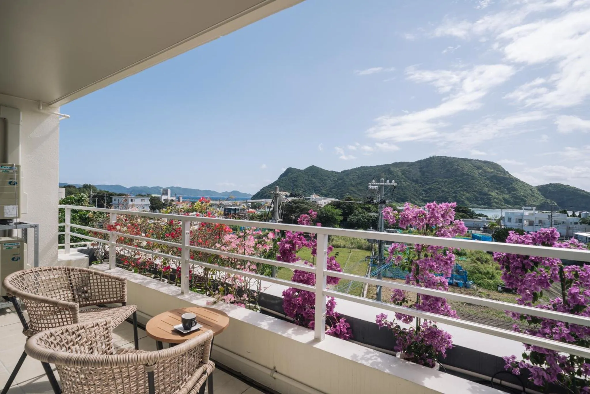 Terrasse aménagée avec mobilier en osier et vue sur la mer et les collines.