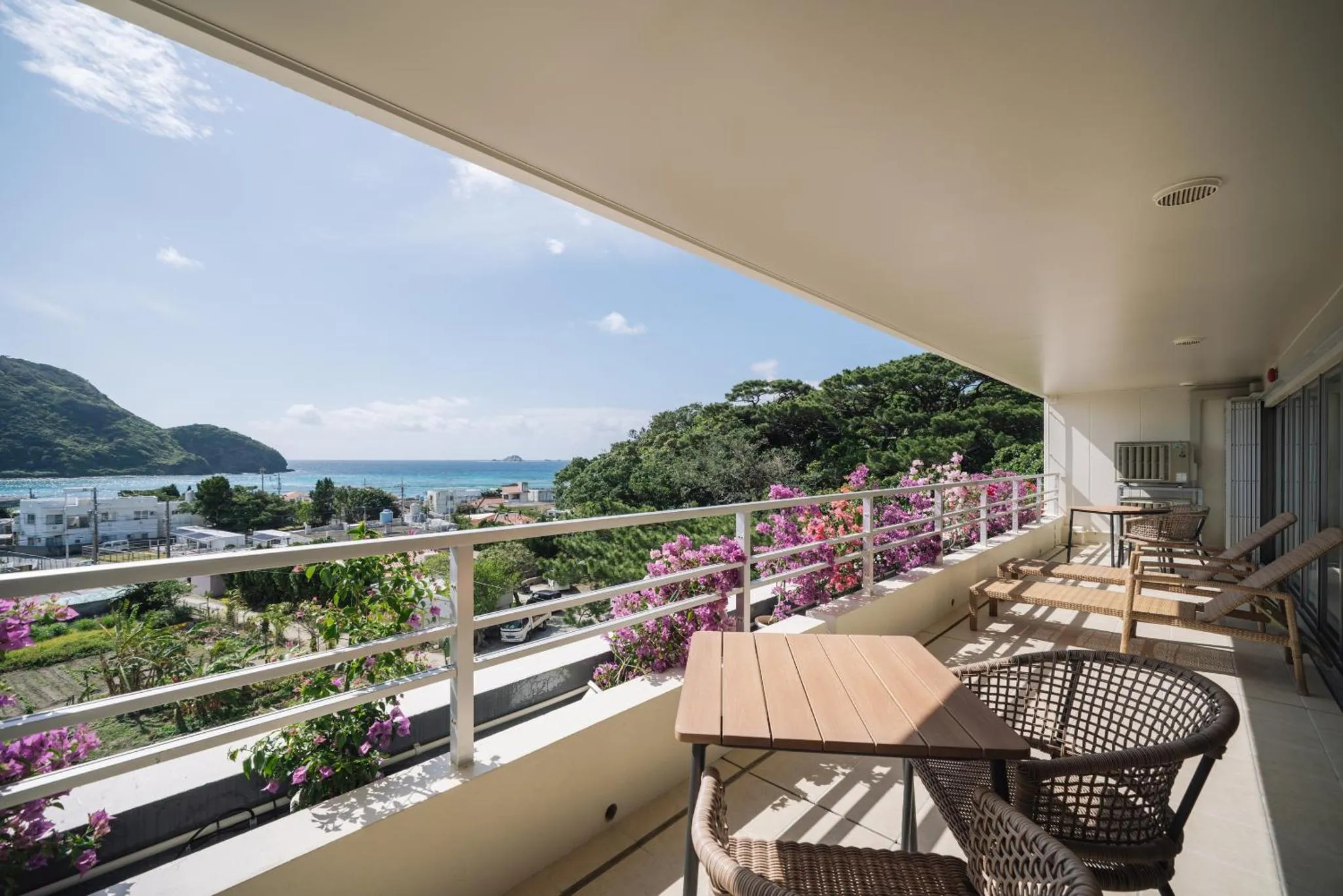 Terrasse fleurie avec vue sur la mer et la végétation.