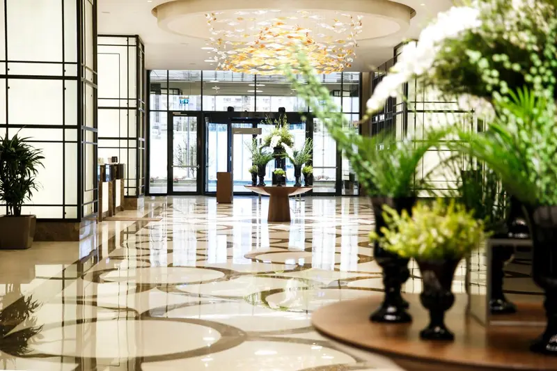 Hall d'entrée lumineux avec sol marbré et décorations florales.