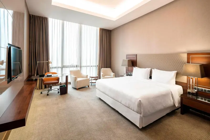 Une chambre d'hôtel lumineuse avec un lit double et un coin salon.