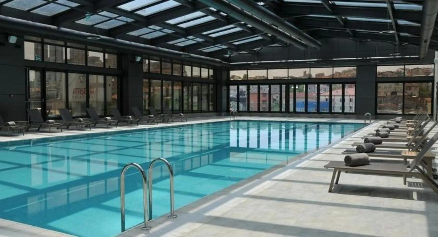 Une piscine interieure avec des transats alignes le long du bassin.