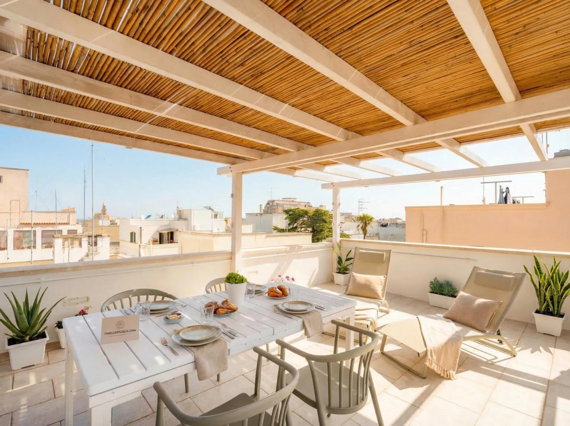 Une table est dressée sur une terrasse ombragée avec vue sur la ville.