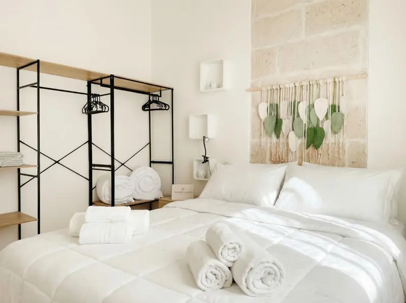 Une chambre lumineuse avec un lit recouvert de linge blanc et des serviettes pliées.
