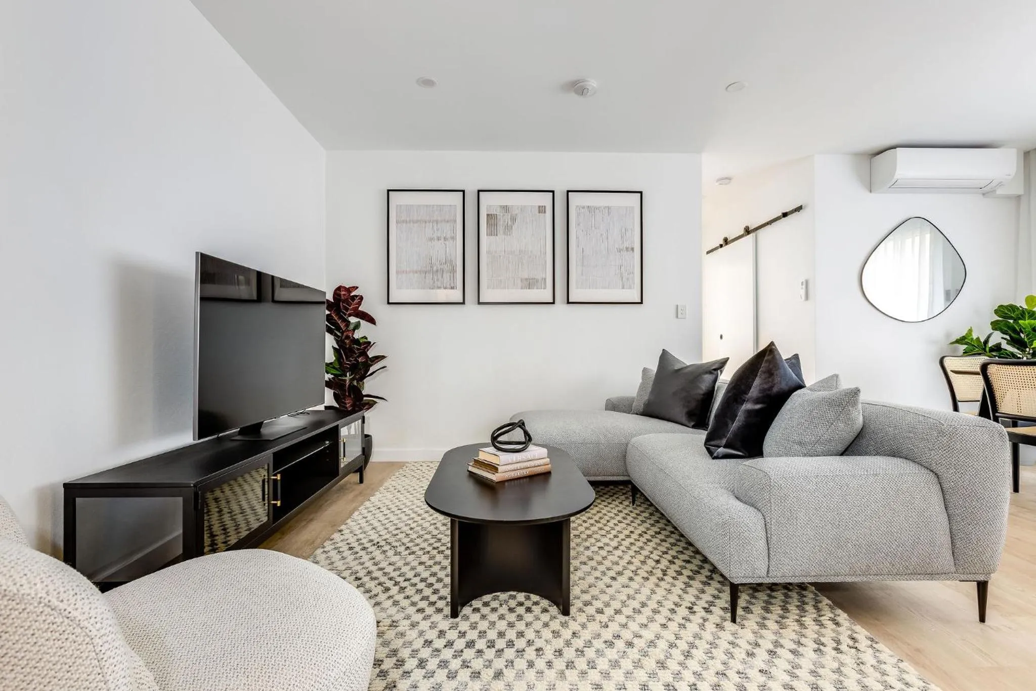 Un salon moderne avec un canapé d'angle, une télévision et des œuvres d'art au mur.