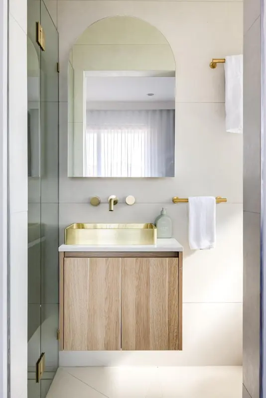 Une salle de bain moderne avec un lavabo doré et un grand miroir.