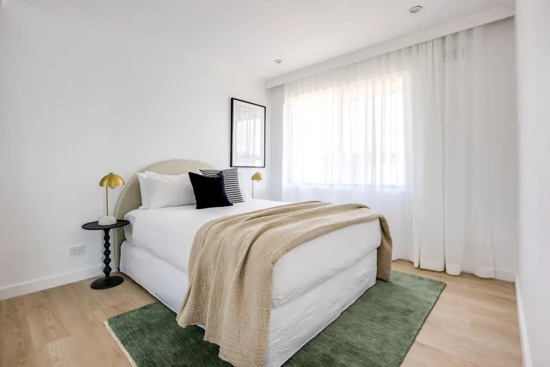 Une chambre lumineuse avec un grand lit et une fenêtre drapée.