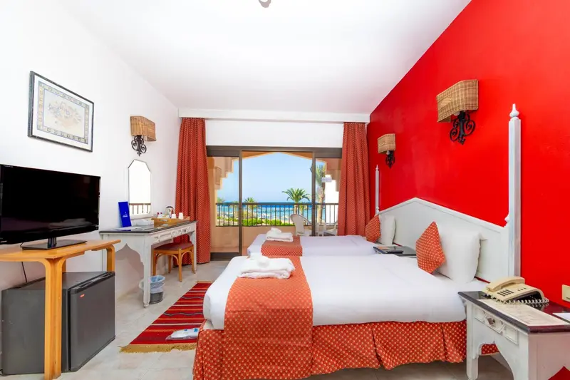 Chambre lumineuse avec un lit double et vue sur la mer.