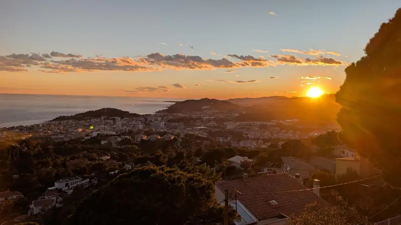Coucher de soleil sur une ville côtière et les montagnes environnantes.