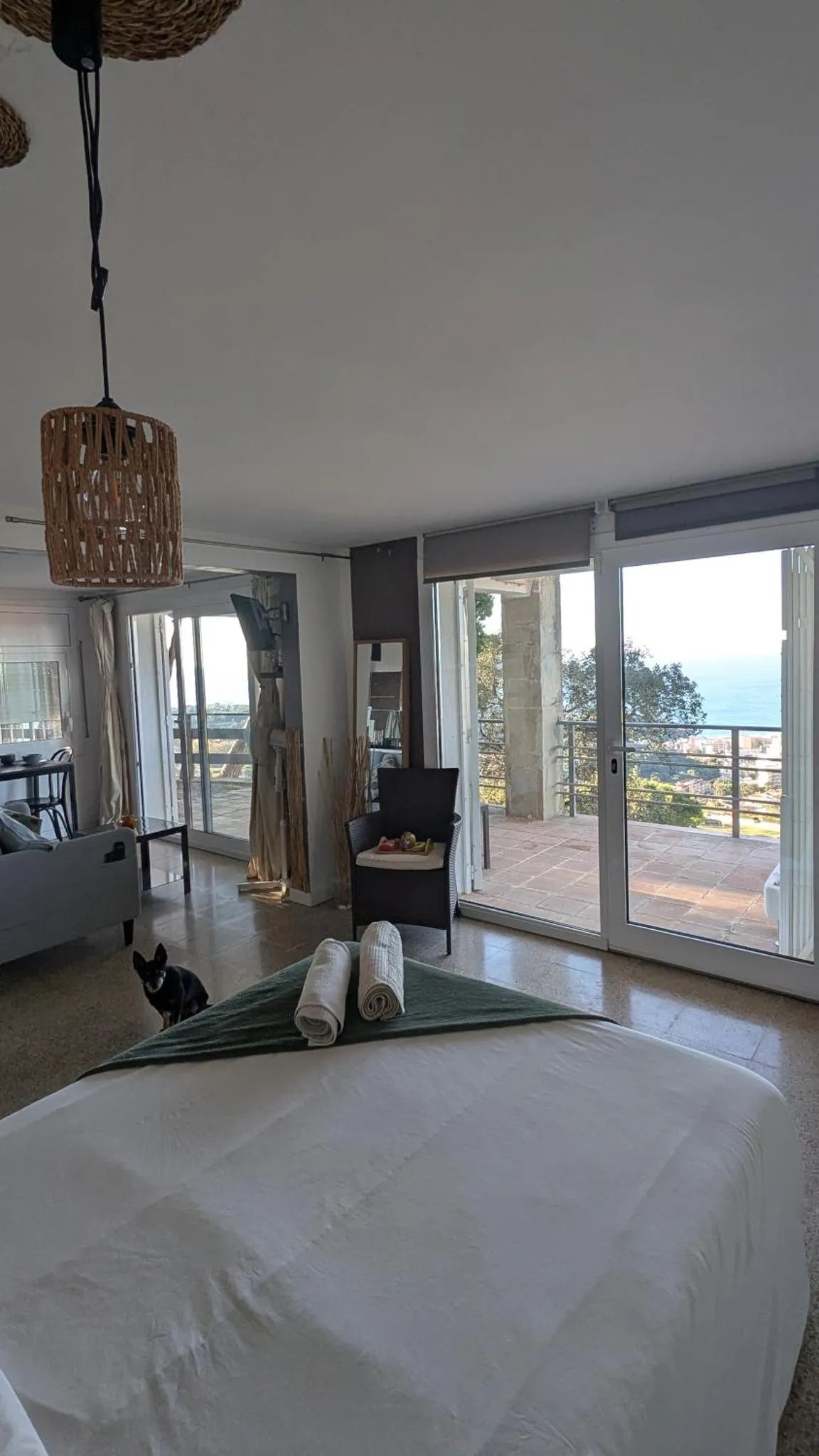 Espace de détente intérieur avec accès à une terrasse ensoleillée et vue sur la mer.