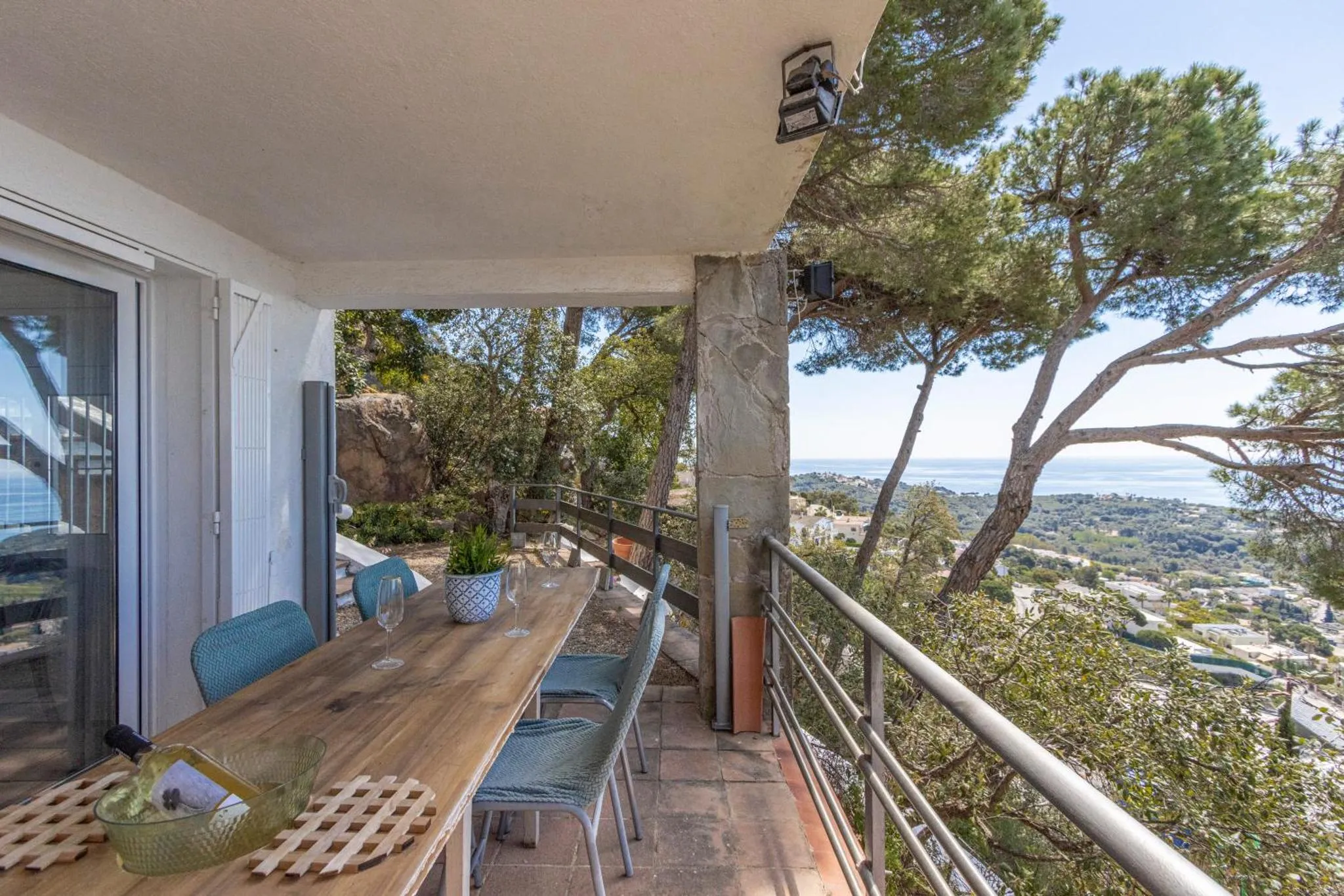 Table et chaises en bois sur une terrasse avec vue sur la mer.